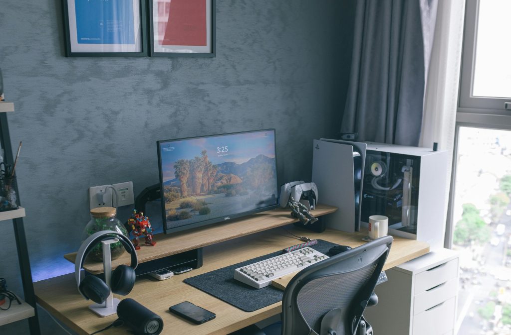 Stylish home office with a monitor, keyboard, and accessories on a wooden desk.